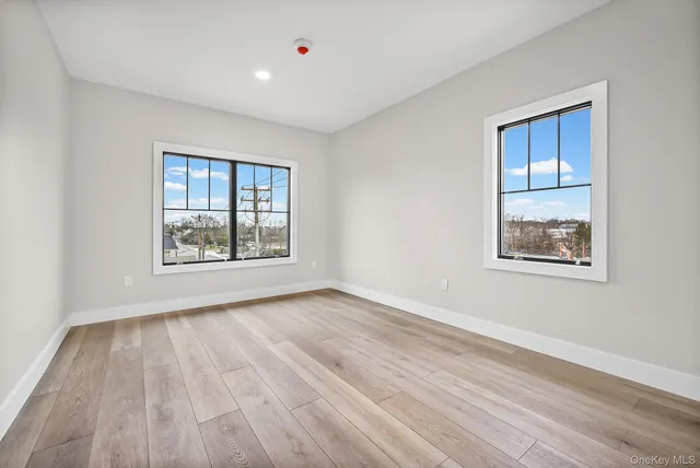 a view of an empty room with window and wooden floor
