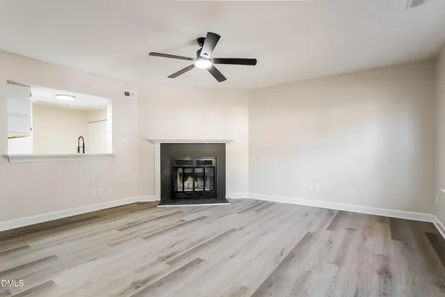 an empty room with wooden floor fireplace and windows