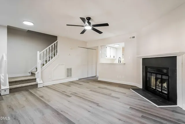 a view of an empty room with wooden floor fireplace and a window