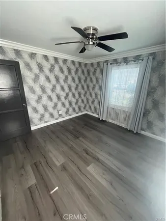 an empty room with wooden floor chandelier fan and windows