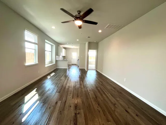 a view of empty room with wooden floor and fan