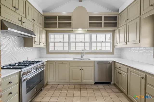 a kitchen with cabinets appliances a sink and a window
