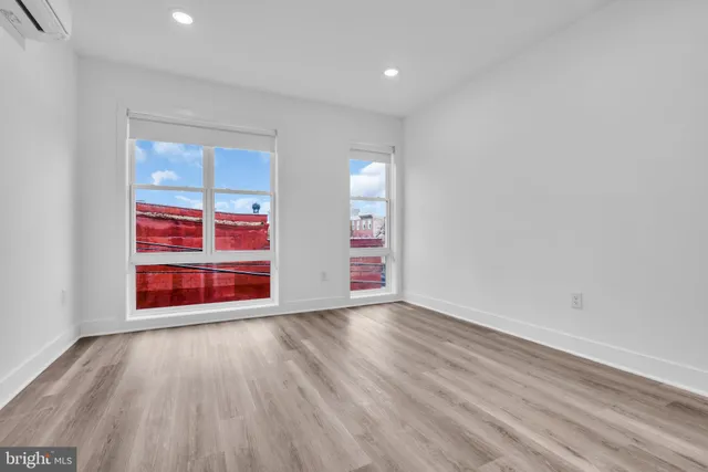a view of an empty room with wooden floor windows and entryway