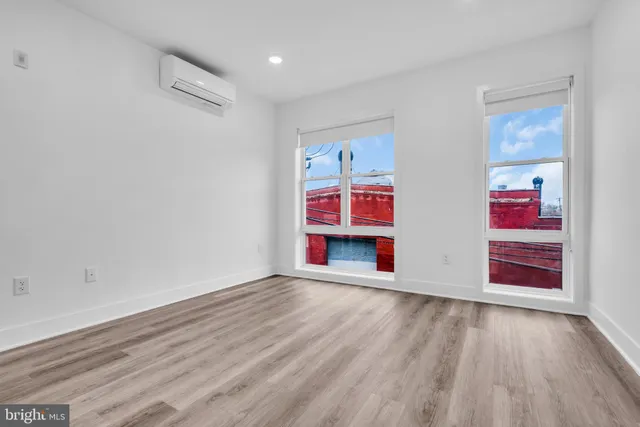 a view of an empty room with window and wooden floor