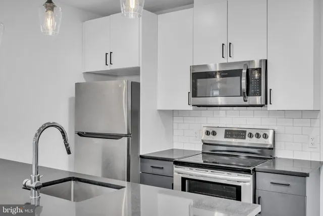 a kitchen with stainless steel appliances a stove a sink and cabinets