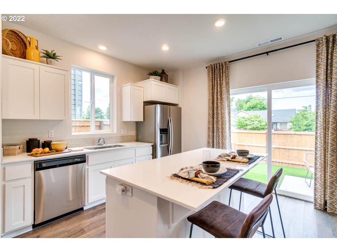 2402 Halter Drive Woodburn, OR 97071 - Photo 16 of 31 a kitchen with a stove a refrigerator a sink a dining table and chairs with wooden floor