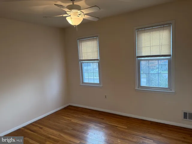 a view of an empty room with wooden floor fireplace and a window