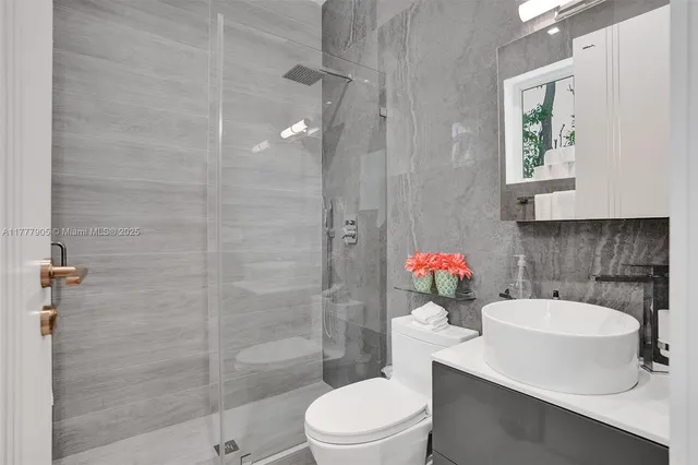 a bathroom with a double vanity sink a toilet and shower