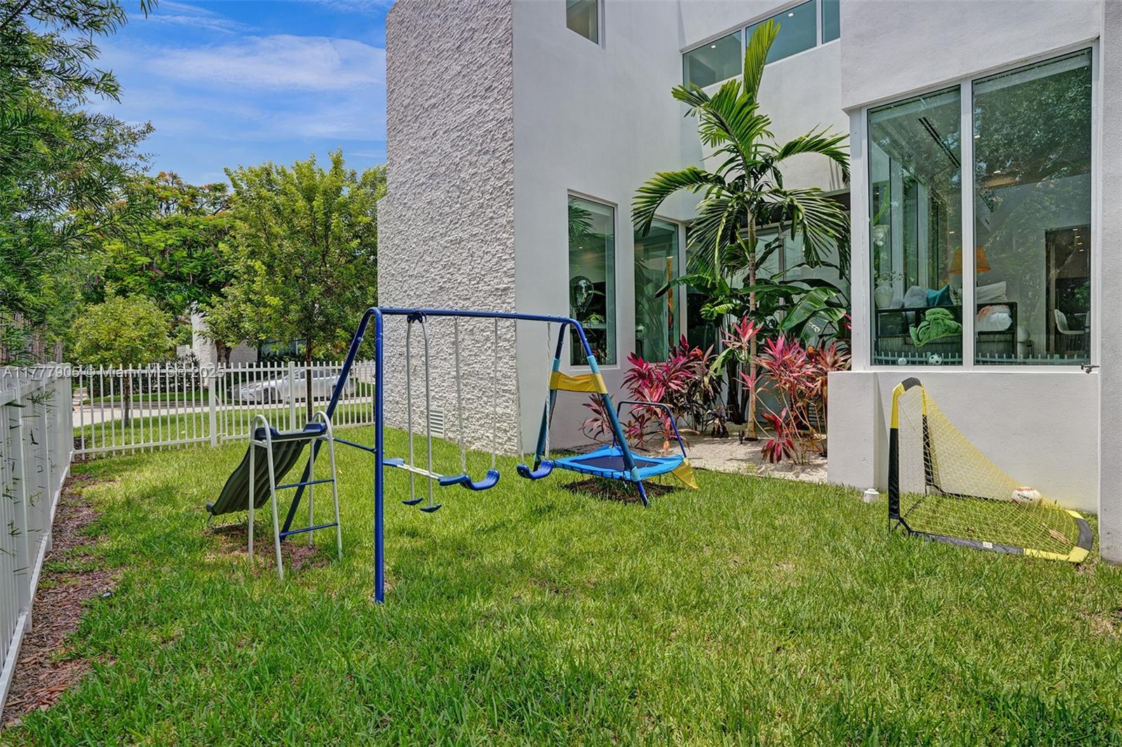 201 Buttonwood Drive Key Biscayne, FL 33149 - Photo 77 of 80 a view of a backyard with a slide trees and wooden fence
