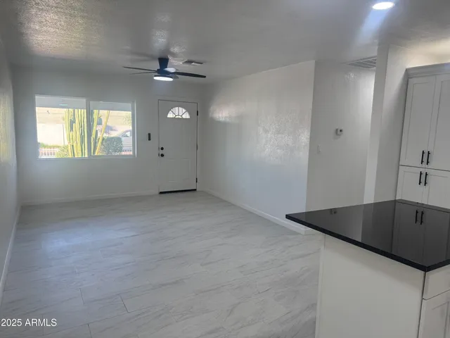 an empty room with windows and ceiling fan