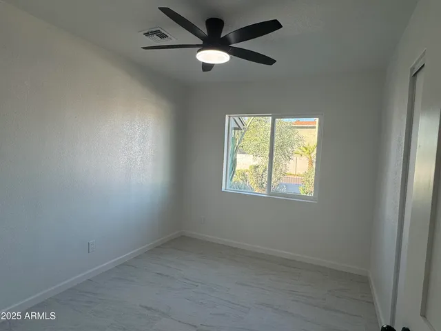 an empty room with a window and a fan