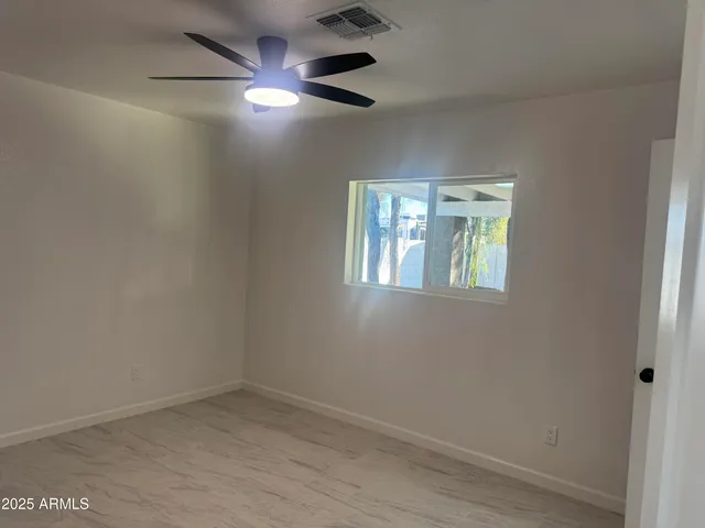 an empty room with a window and a fan