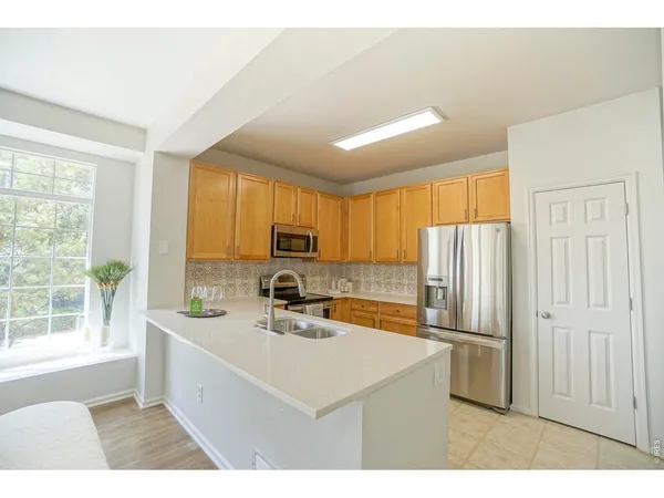 a kitchen with stainless steel appliances a refrigerator a sink a stove and white cabinets
