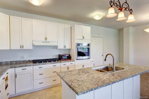 a kitchen with granite countertop a sink a counter top space cabinets and stainless steel appliances