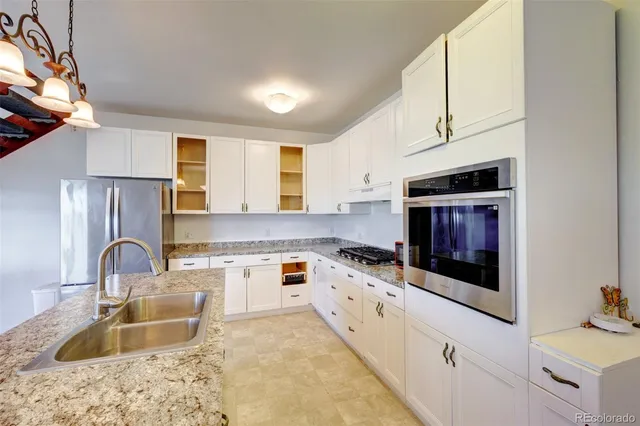 a kitchen with granite countertop a sink stove and cabinets
