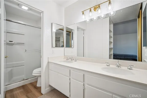 a bathroom with a double vanity sink toilet mirror and shower