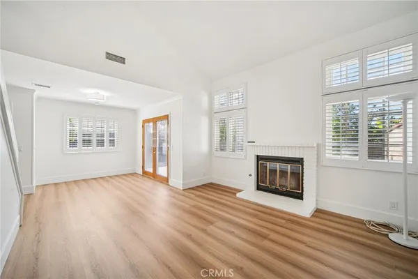 an empty room with windows fireplace and wooden floor