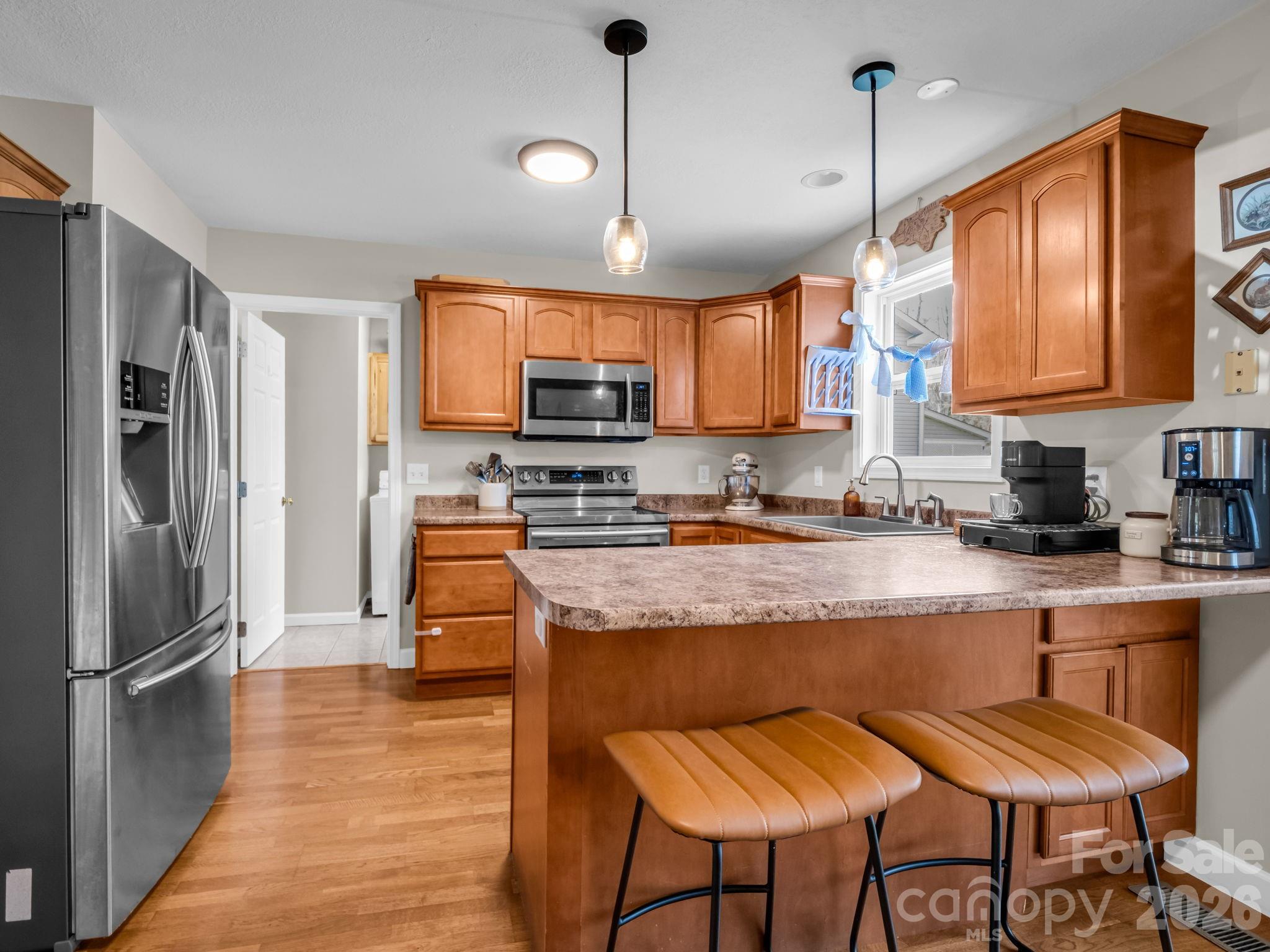 22 Macks Way Hendersonville, NC 28739 - Photo 12 of 42 a kitchen with stainless steel appliances granite countertop a stove a refrigerator a kitchen island a sink dishwasher a dining table and chairs with wooden floor