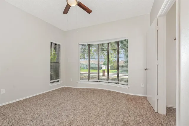 an empty room with chandelier fan and windows