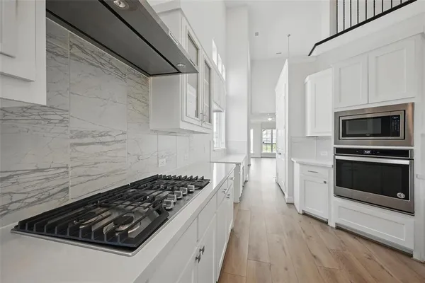 a kitchen with granite countertop stainless steel appliances a stove refrigerator and cabinets