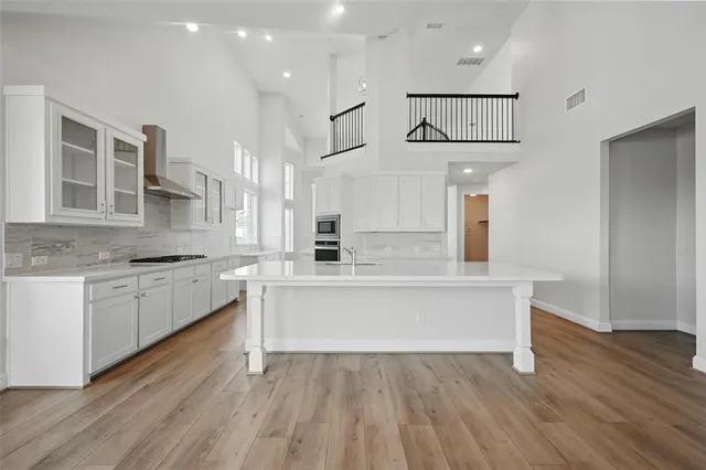a large white kitchen with wooden floors and stainless steel appliances