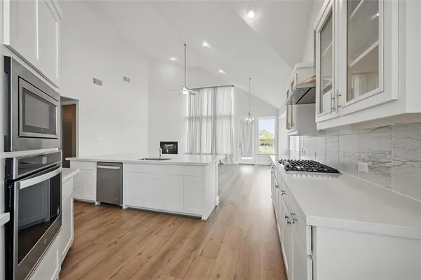 a kitchen with a sink a counter top space stainless steel appliances and cabinets
