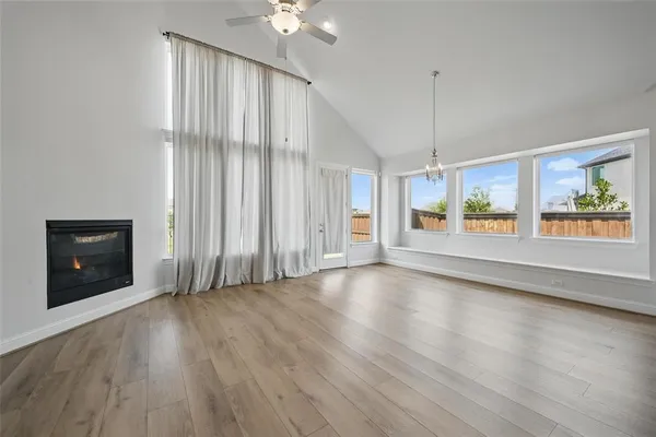 an empty room with wooden floor chandelier and windows