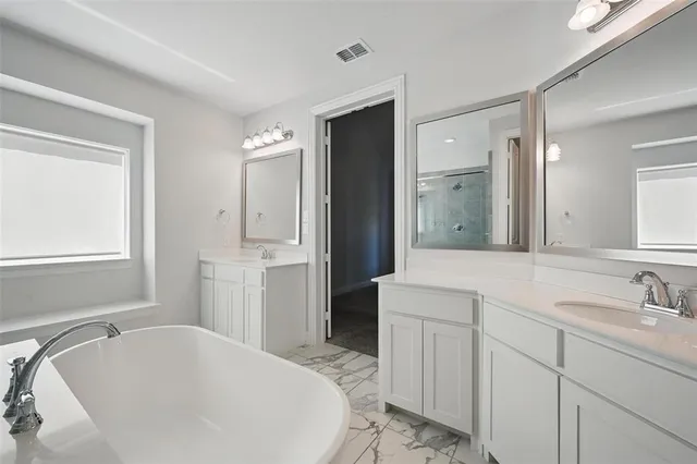 a spacious bathroom with a tub sink and mirror