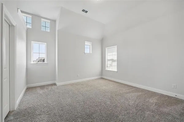 a view of an empty room with wooden floor and windows