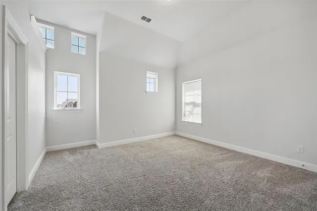 a view of an empty room with wooden floor and windows