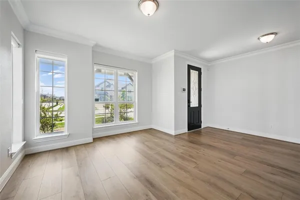 an empty room with wooden floor and windows