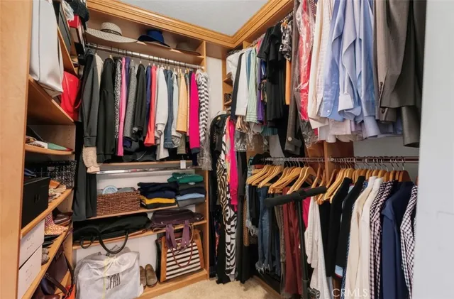 a view of walk in closet with clothes and shoes