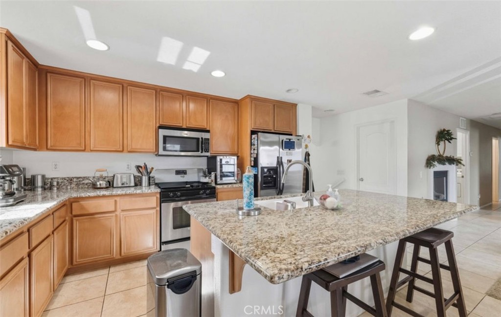 10326 Sparkling Drive, Unit 1 Rancho Cucamonga, CA 91730 - Photo 4 of 34 a kitchen with kitchen island granite countertop a table chairs microwave and refrigerator