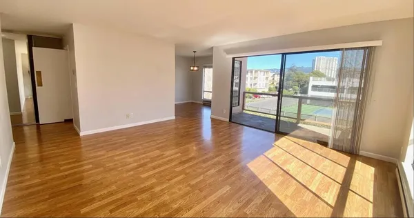 a view of empty room with wooden floor and fan