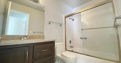 a bathroom with a granite countertop sink toilet and shower