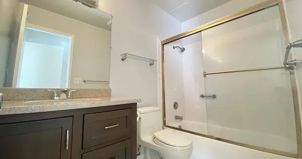 a bathroom with a granite countertop sink toilet and shower