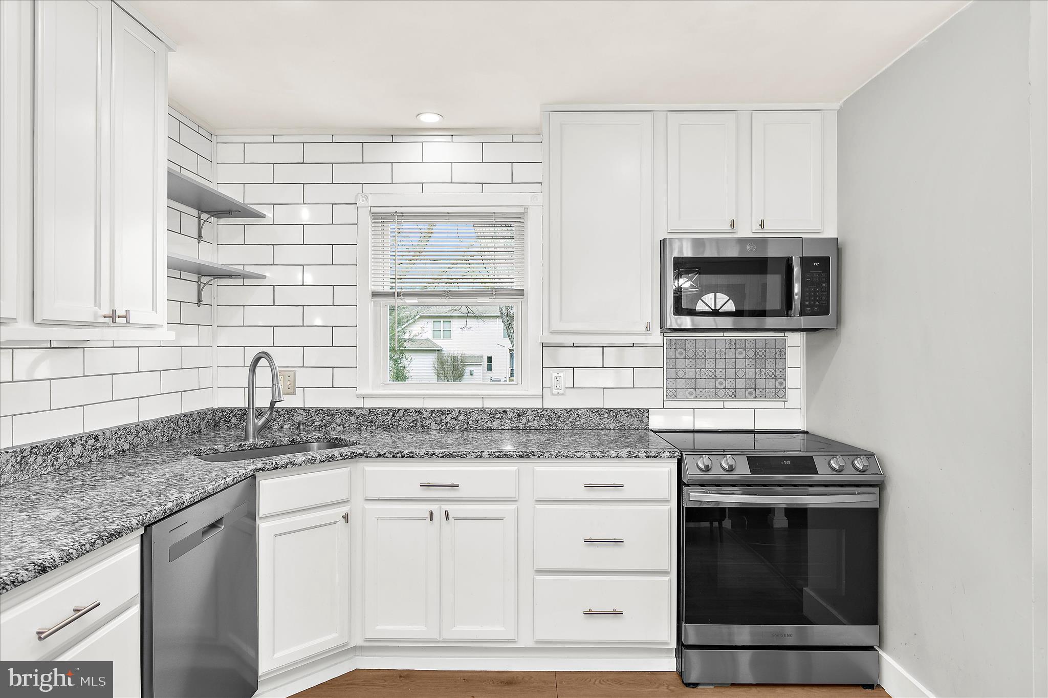 9140 Vollmerhausen Road Savage, MD 20794 - Photo 12 of 49 a kitchen with granite countertop a stove sink and microwave