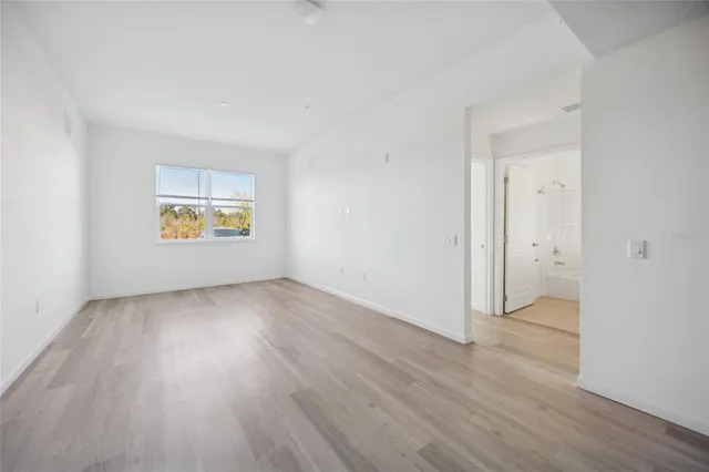 an empty room with a window and wooden floor