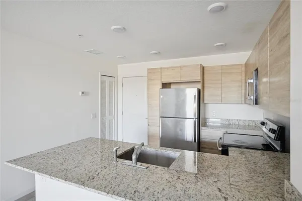 a kitchen with stainless steel appliances granite countertop a refrigerator a stove and a sink