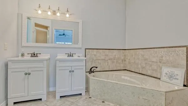 a bathroom with a bathtub a sink a mirror and vanity