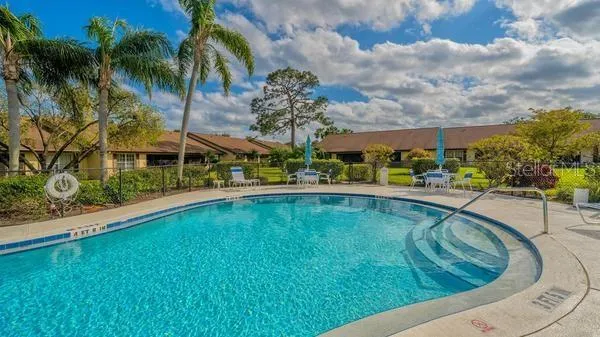 a view of a swimming pool with lawn chairs under an umbrella