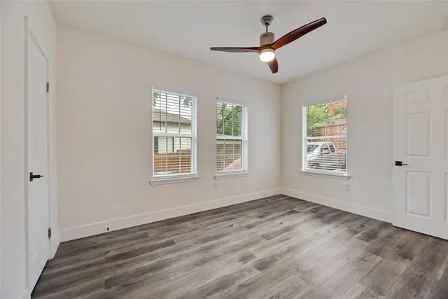 a view of empty room with wooden floor and fan