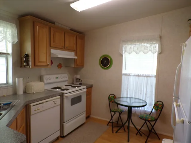 a kitchen with a stove a sink cabinets and a window