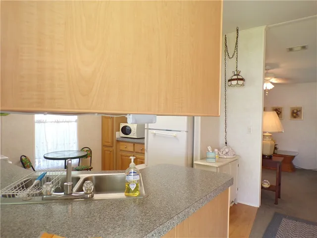 a view of a kitchen with kitchen island a sink a stove and a dining table with wooden floor