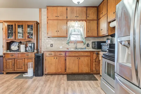 a kitchen with stainless steel appliances granite countertop a stove a sink and a refrigerator with wooden floors