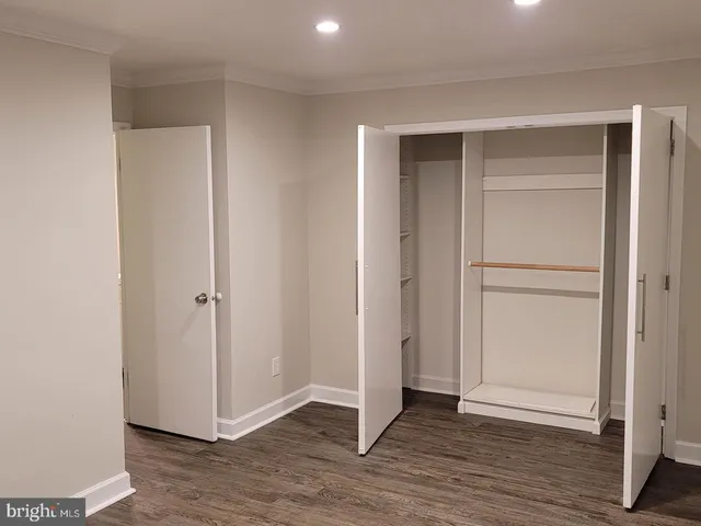 a view of an empty room with wooden floor & closet