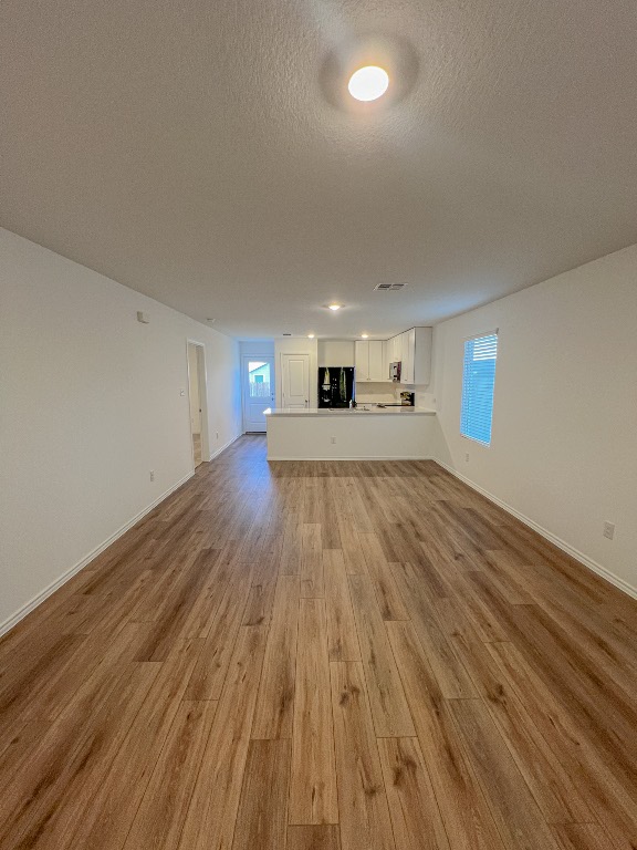 129 Hellcats Way Jarrell, TX 76537 - Photo 4 of 19 Unfurnished living room with light wood-style floors and a textured ceiling