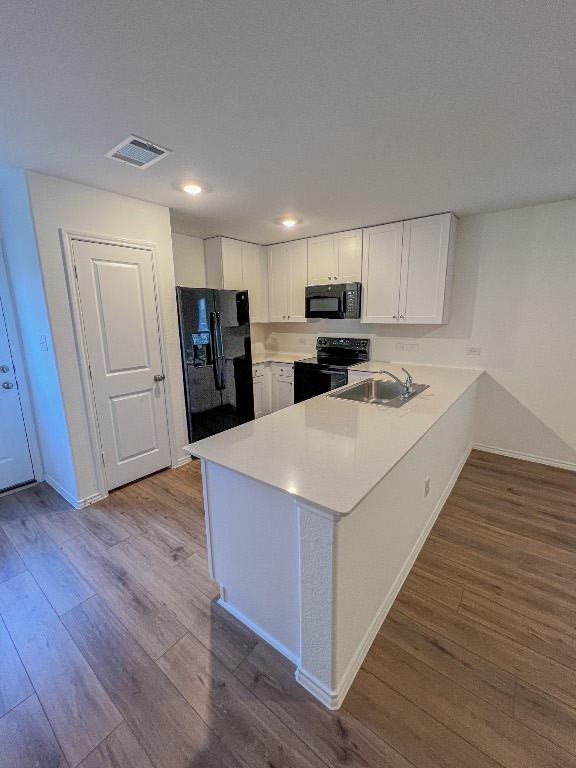129 Hellcats Way Jarrell, TX 76537 - Photo 9 of 19 Kitchen featuring white cabinets, light countertops, a peninsula, black appliances, and recessed lighting