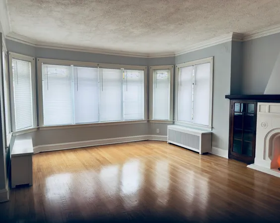 a view of an empty room with a window and wooden floor