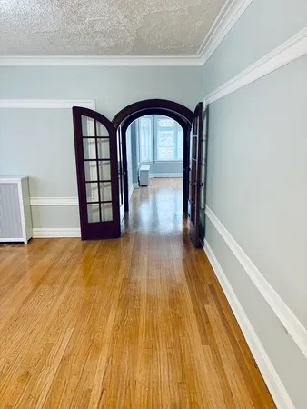 a view of empty room with wooden floor and fan